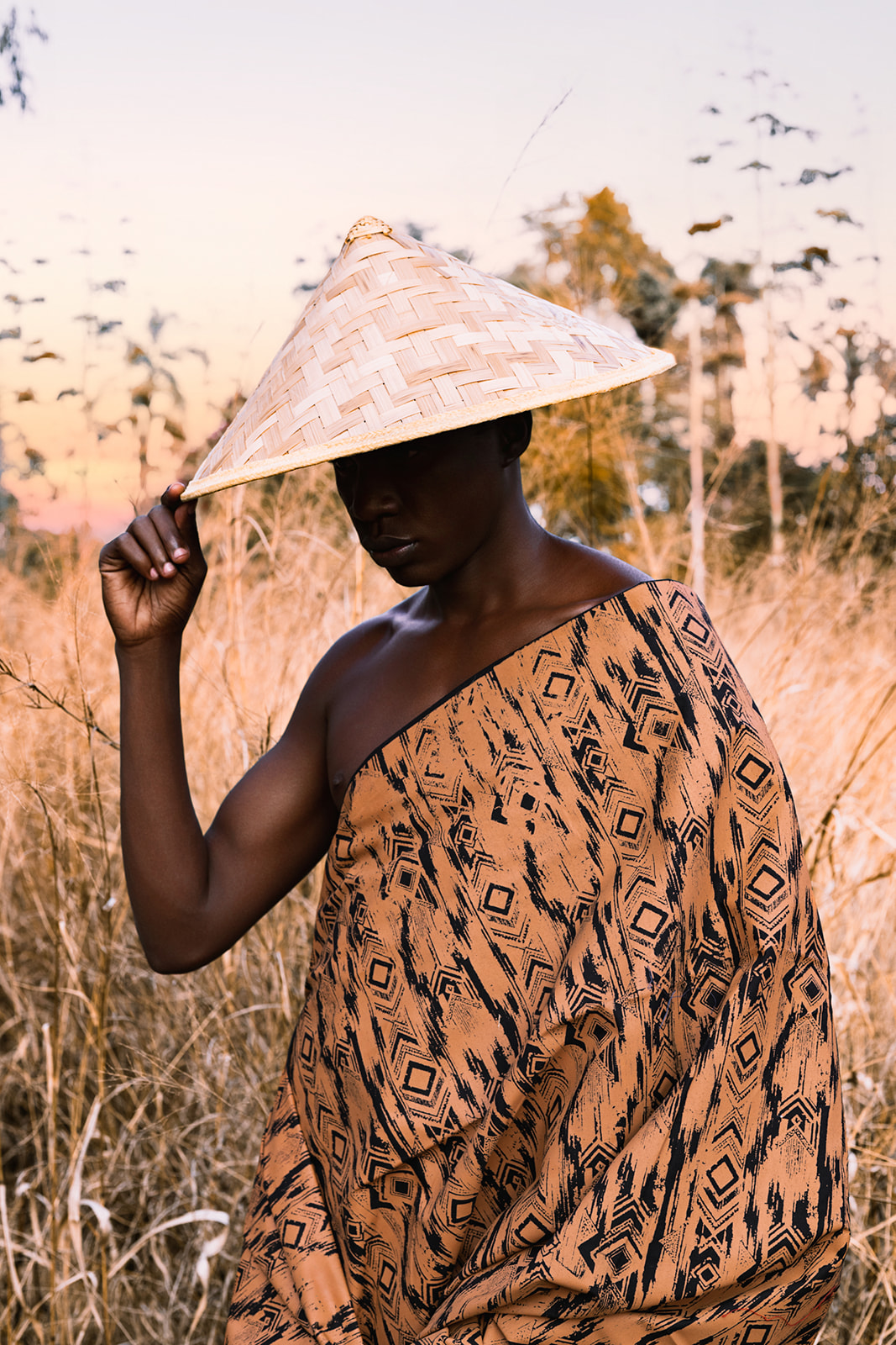 Two models in MOSI wraps and conical hats, one in ochre/black, one in white geometric print.