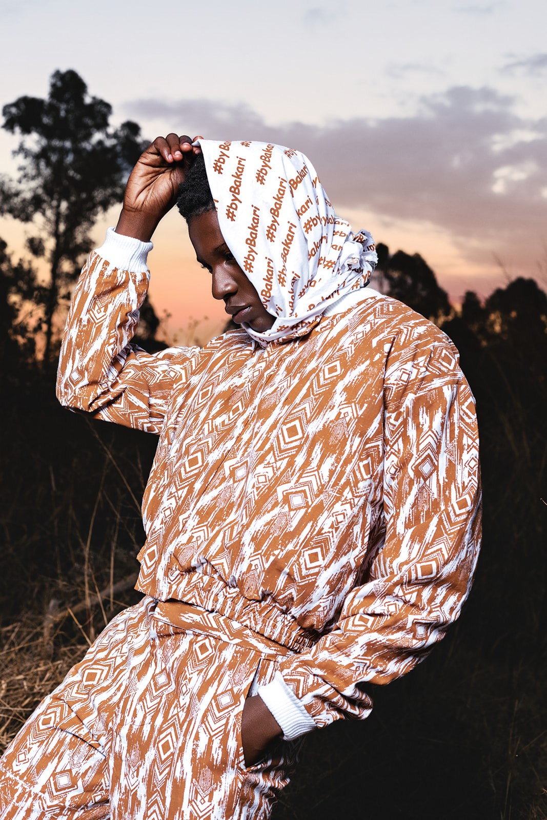 Two models in MOSI prints, white and ochre coordinates, intimate pose at dusk landscape.