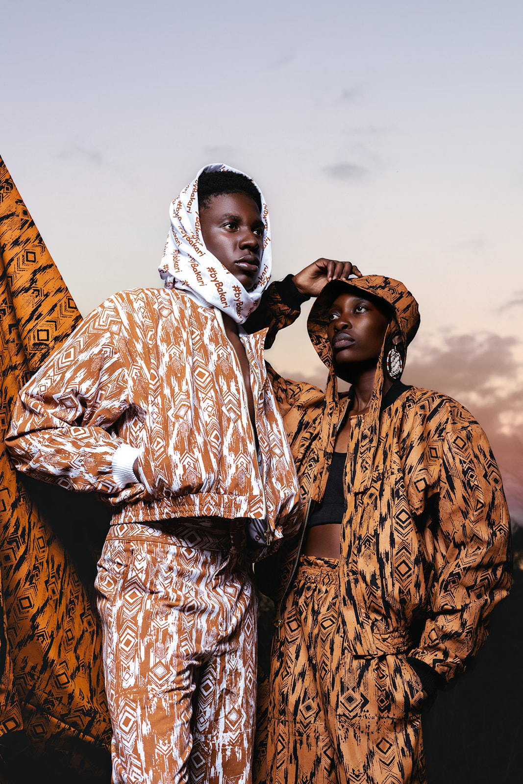 Shirtless male model in ochre MOSI print pants with geometric collar detail, standing confidently.